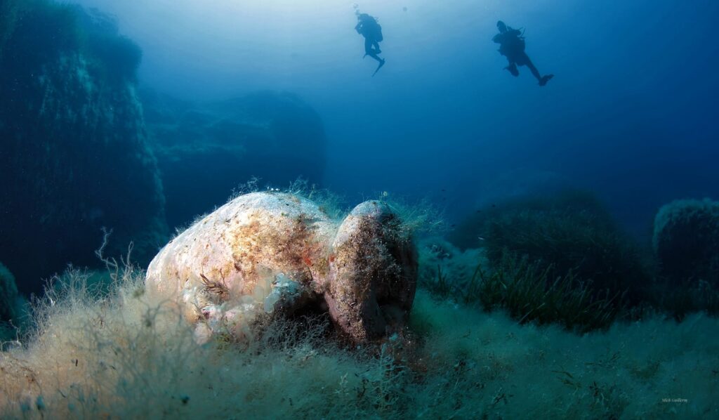 Photo d'une amphore et de deux plongeurs en arrière plan